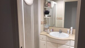 Ein Badezimmer mit einem weißen Waschbecken, einem Spiegel und einem Ablagebereich für Toilettenartikel.