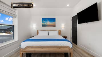 Une chambre à coucher avec un lit, un tableau, une télévision et une fenêtre.