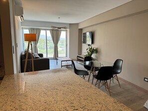 Relax in a spacious living room with a casual seating area, dining space, and large window offering a serene view.