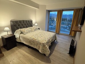 Relax in a spacious room with a large bed, tufted headboard, and city views.