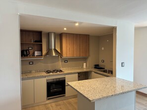 Enjoy cooking in this well-lit kitchen with an oven and wooden cabinetry.