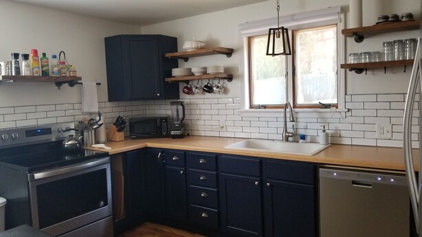 A kitchen with dark blue cabinets, a wooden countertop, a stainless steel stove, a microwave, and a dishwasher. - Adventure House: Fully Stocked Kitchen 5 mins from Michigan Tech (Hancock)