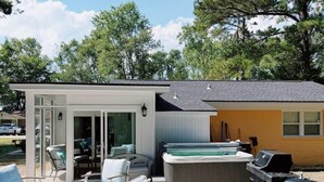 Un espace de vie extérieur moderne, doté d’un jacuzzi, d’un barbecue et de coins salon.