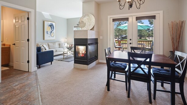 A living room with a fireplace, a dining table with chairs, a sofa, and a coffee table.