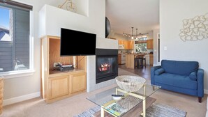 A modern living room with a fireplace, television, and a blue sofa.