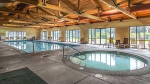 A large indoor swimming pool with a wooden ceiling and large windows.