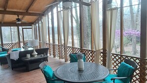 A covered outdoor area with a round table and chairs, a sofa, and a ceiling fan. - Serene Lakefront Cottage Home, relax and enjoy! Walk right to the water. (Westview)