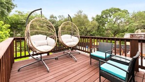 Een houten terras met twee rieten stoelen en een tafel.