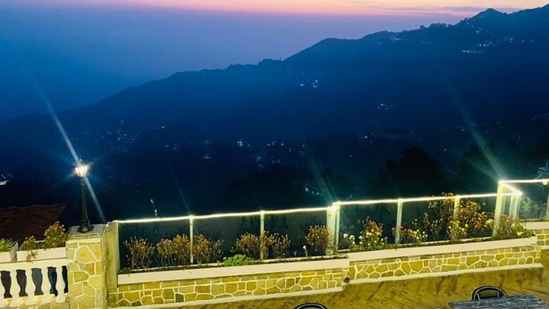 A night view of a mountainous landscape with a stone wall and railing in the foreground. - Shashwat Grand Valley (Dehradun)