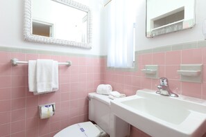 A bathroom with pink tiles, a white sink, and a toilet. - Beach Tree across street from beach (Siesta Key)