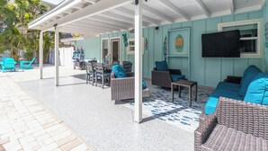 A covered outdoor seating area with wicker furniture and a tiled floor.