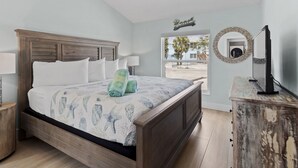 A bedroom with a wooden bed, a round mirror, and a view of the outside.