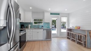 A modern kitchen with stainless steel appliances, a tiled backsplash, and a bar area with stools.