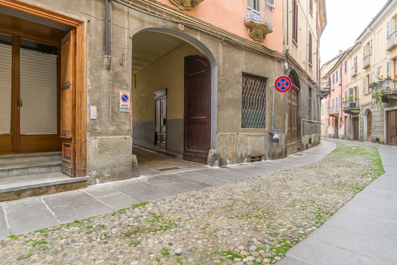 A building with an arched entrance, a closed shutter door, and a no parking sign.