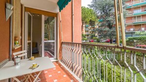 Un balcon avec une table, des chaises et une vue sur un immeuble à plusieurs étages, lui aussi doté de balcons.