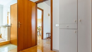 Une pièce avec une porte en bois, une armoire blanche et un sol carrelé.
