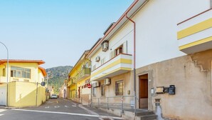 Une rue étroite, bordée de bâtiments des deux côtés, un ciel dégagé et une voiture garée le long de la rue.
