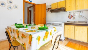 Une cuisine compacte avec des meubles en bois, une cuisinière et un coin repas avec une table mise pour deux personnes.
