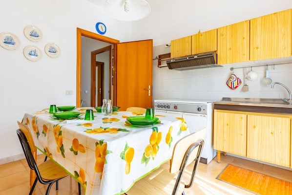 A compact kitchen with wooden cabinets, a stove, and a dining area with a table set for two.