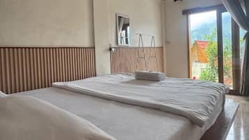 Ein Zimmer mit zwei Betten, einem Spiegel und Blick ins Freie.