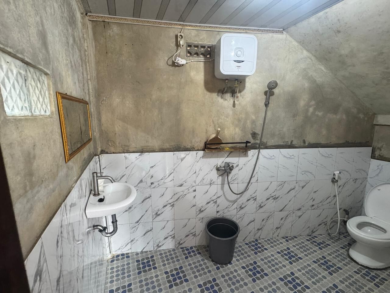 A bathroom with a sink, toilet, shower, and a water heater.