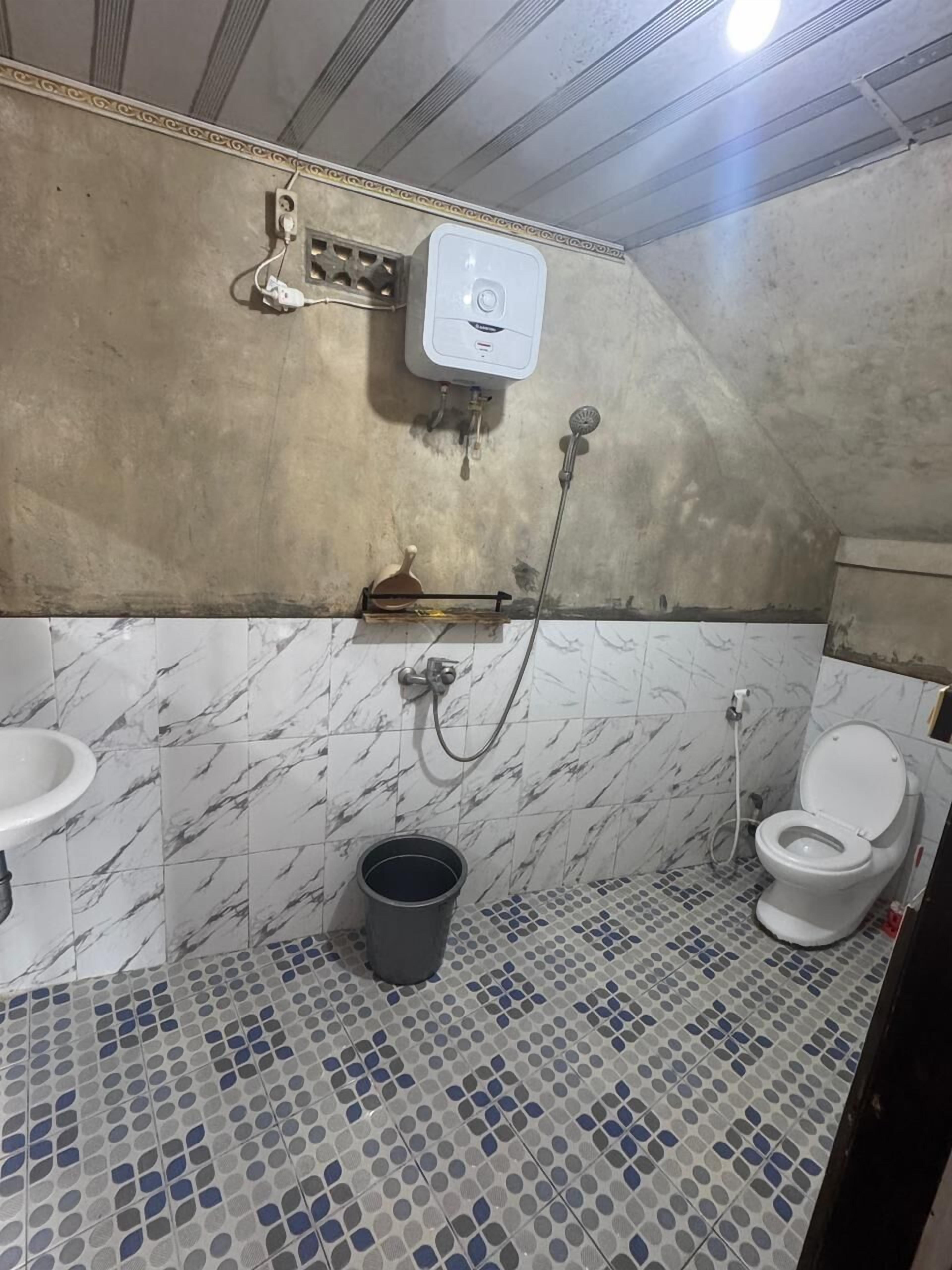 A bathroom with a toilet, sink, shower, and a marble-tiled floor.