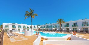 Ein Hotelpoolbereich mit Liegestühlen und Palmen.