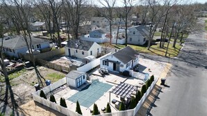Un barrio residencial con una casa grande que cuenta con un amplio patio trasero, una piscina, un patio amurallado y un cobertizo pequeño.