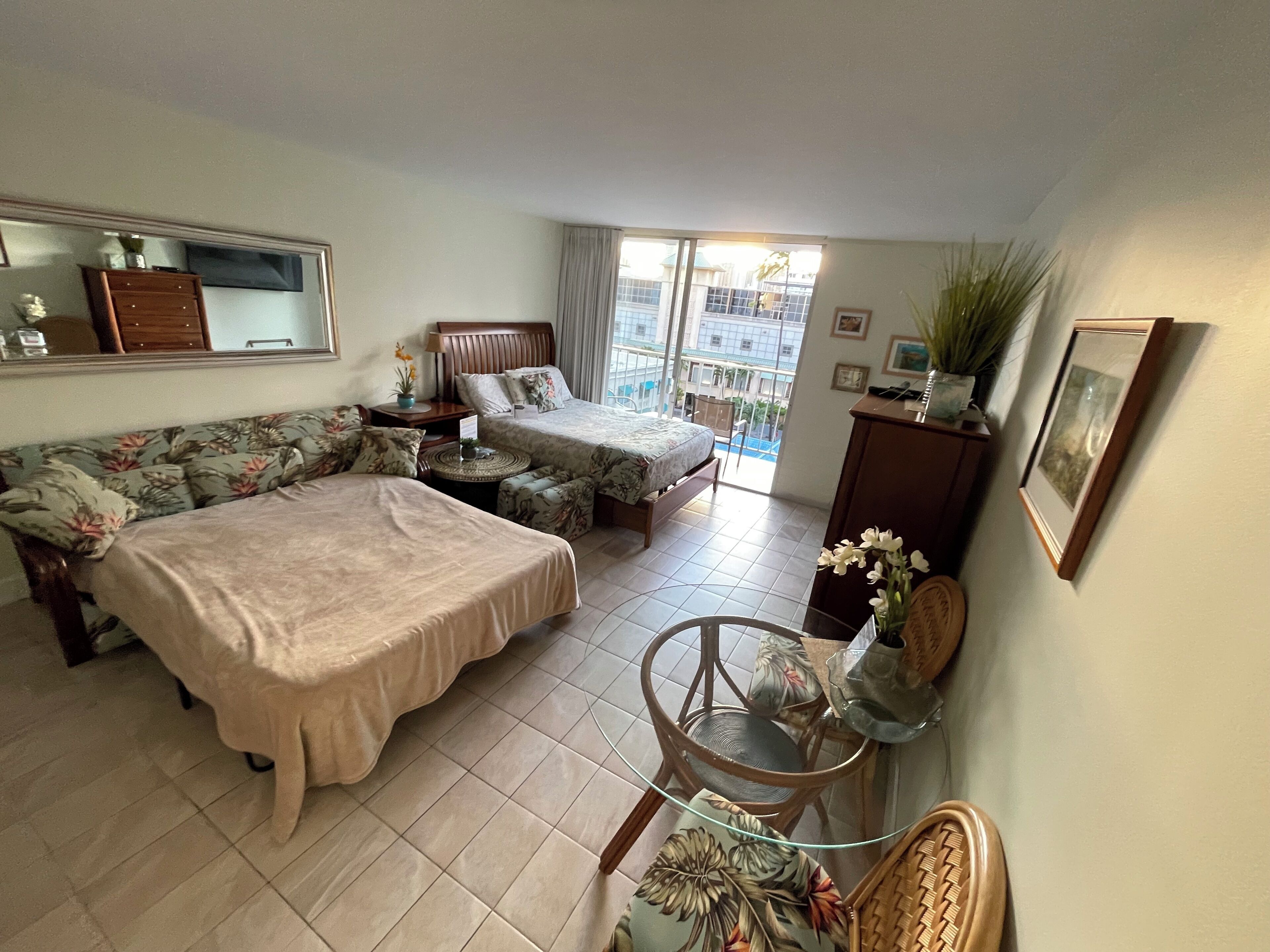 A hotel room with two beds, a sofa, a small table, and a chair.