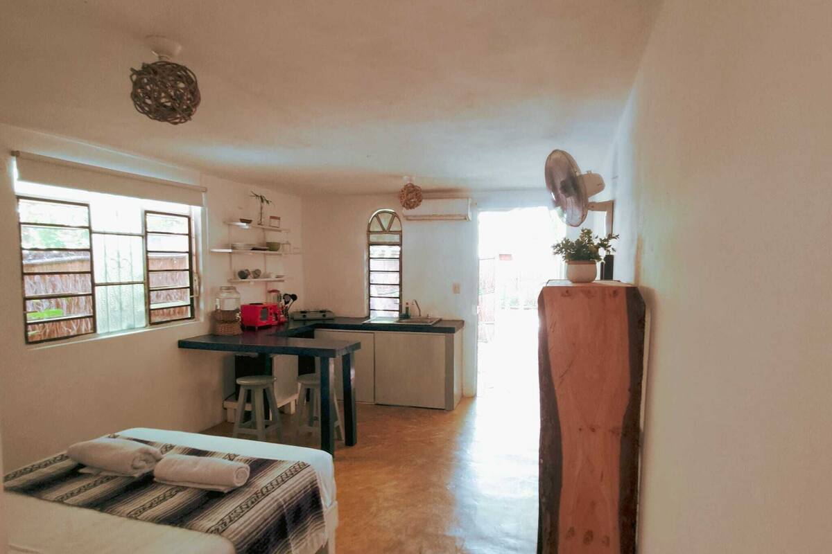 Una habitación compacta con cama, una kitchenette pequeña y una zona de comedor.