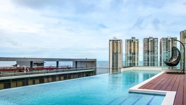 Ein Infinity-Pool auf dem Dach mit Blick auf hohe Gebäude und eine Brücke.