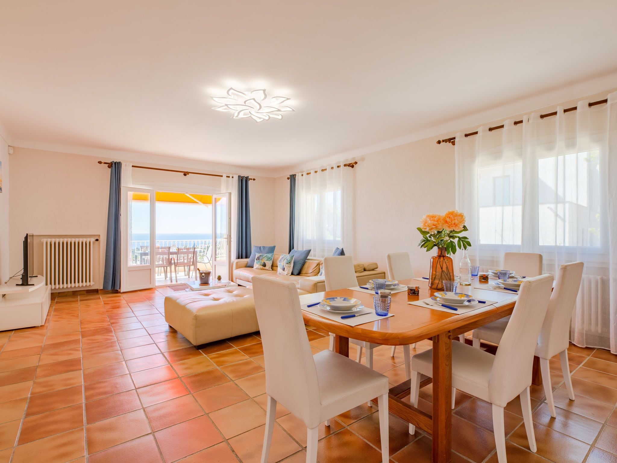 A spacious living room with a dining area, a sofa set, and a view to the outside.