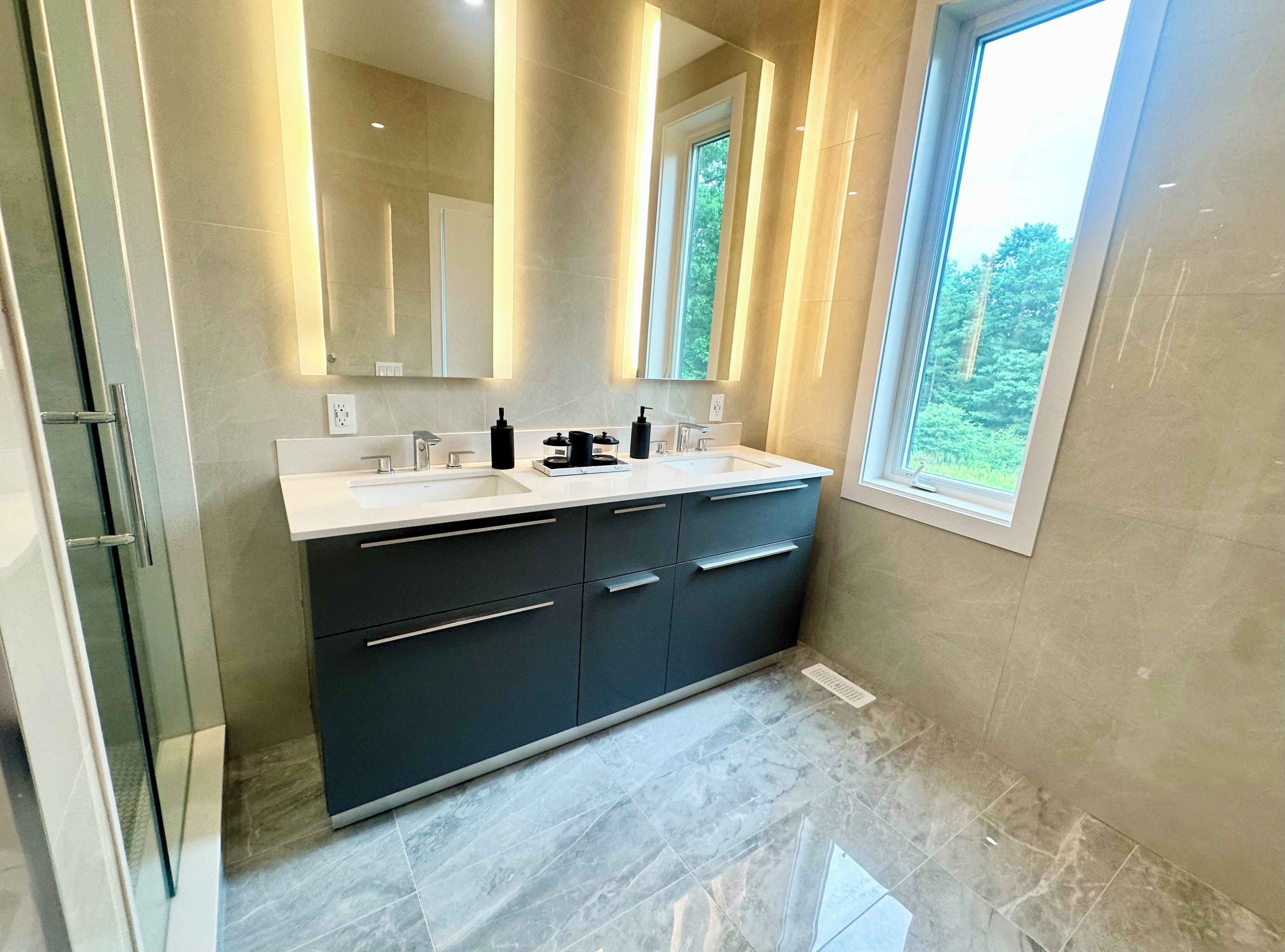 A modern bathroom with a large vanity, two sinks, and a large mirror.