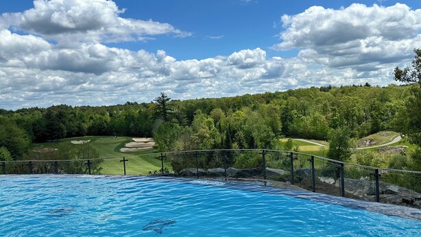 A swimming pool with a view of a golf course and surrounding greenery.