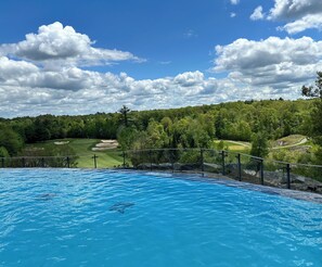 A swimming pool with a view of a golf course and surrounding greenery.