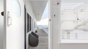 Un couloir donnant sur la mer, une fenêtre avec des stores et une plante en pot.
