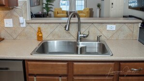 A kitchen with a stainless steel sink, wooden cabinets, and a countertop. - Cozy 4BR Retreat Near Randolph AFB & Ft Sam (Converse)