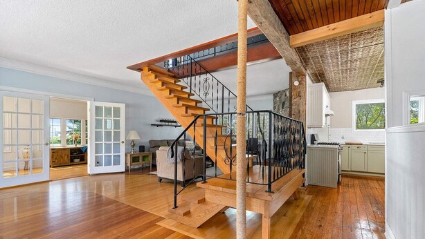 Un grand espace de vie comprenant un escalier en bois, un arbre à chat et un coin cuisine.