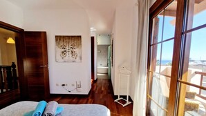Ein Hotelzimmer mit Bett, Meerblick und einem durchgegangenen Badezimmer.