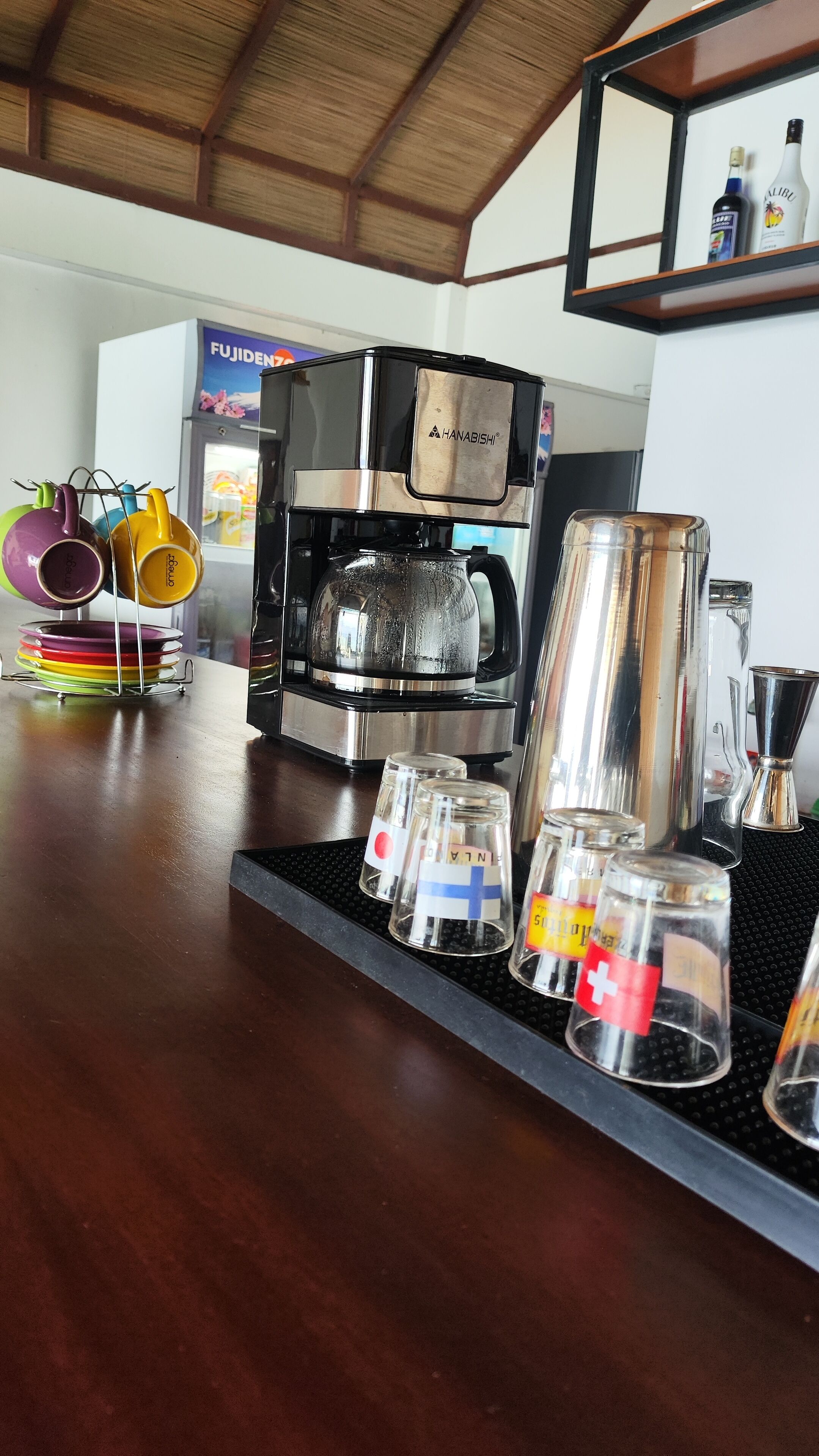 A bar area with a coffee machine, glasses, and bottles.
