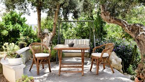 Une terrasse extérieure avec une table et des chaises, entourée de verdure et de plantes.