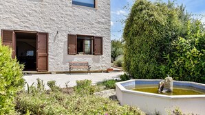 Un bâtiment en pierre avec un banc et une fontaine dans le jardin.