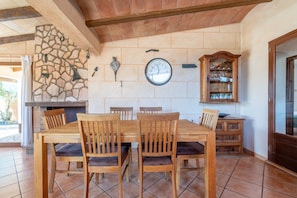 A dining area with a stone wall, a clock, and a wooden cabinet with glassware.