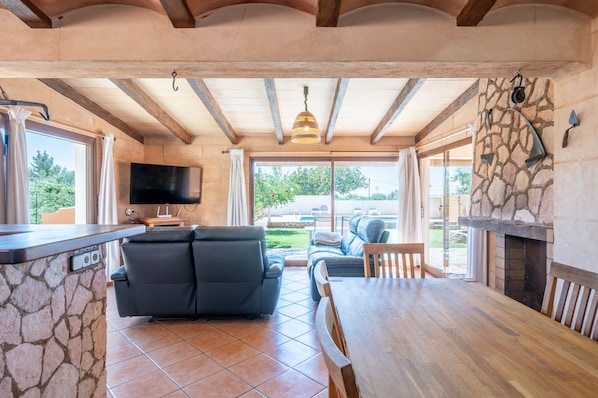 A modern interior with a stone wall, a flat-screen TV, a sofa, a dining table, and a fireplace.