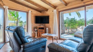 Um quarto com dois sofás de couro, uma televisão, uma mesinha e uma parede de pedra.