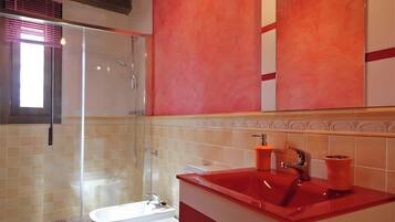 Un bagno moderno con box doccia in vetro, una vasca da bagno bianca e un lavandino rosso.