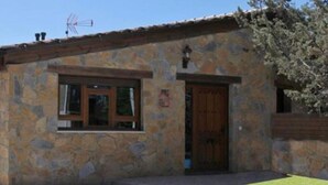 Un edificio de piedra con puerta y ventana de madera, un pequeño porche y cielo despejado.