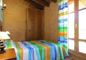 Une pièce avec un lit, une lampe, une fenêtre avec des rideaux et une porte.