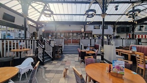 An indoor restaurant with a high ceiling, wooden tables, and chairs. There is a bar area in the background. - 1 Bed Studio Sleeps 4 - Seaside, Dog Friendly (Bridlington)