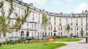 A row of white, multi-story residential buildings with a paved walkway in front. - 1 Bed Studio Sleeps 4 - Seaside, Dog Friendly (Bridlington)